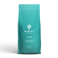 A turquoise bag displays the Purity Coffee logo, advertising their Flow medium-roasted organic whole bean coffee blend.
