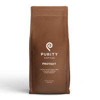 A brown bag displays Purity Coffee's "Protect," a medium roast organic whole bean coffee crafted for liver vitality.
