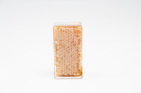 Beeswax honeycomb sits encased in a clear plastic container, showcasing natural honey.
