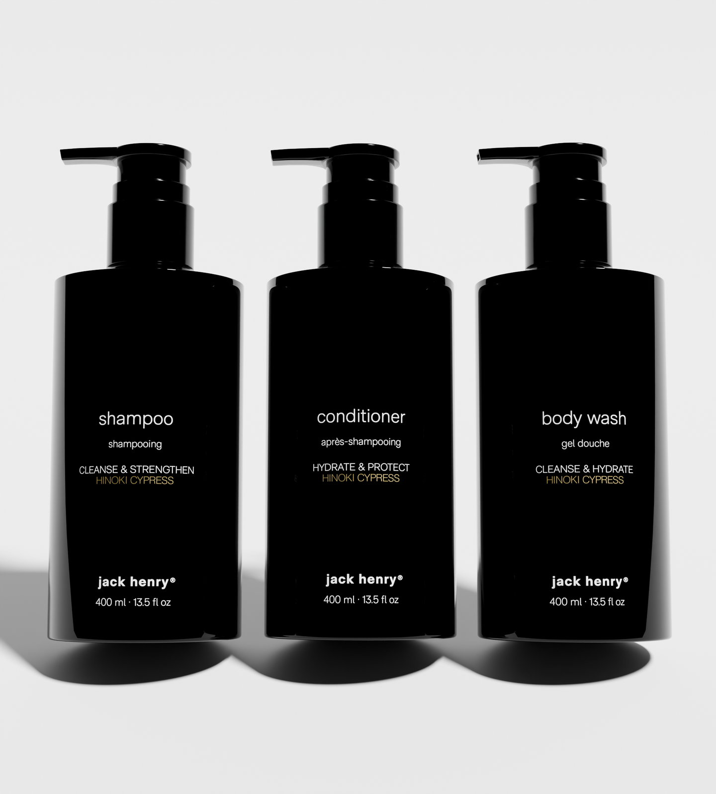 Three black pump bottles showcase Jack Henry shampoo, conditioner, and body wash with Hinoki Cypress scent.
