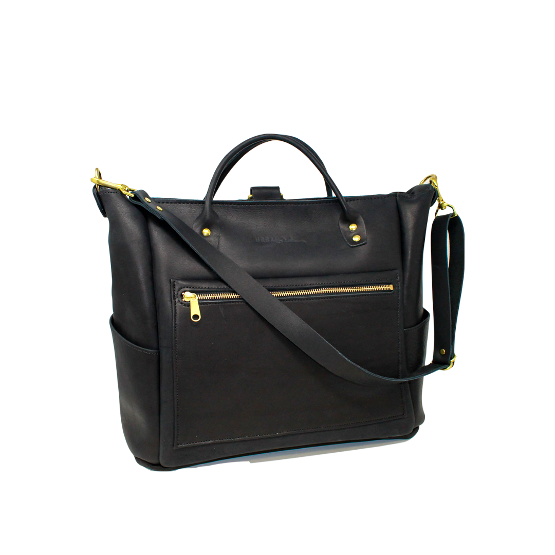 A stylish black leather tote bag with gold zippers and crossbody strap sits on a white background.
