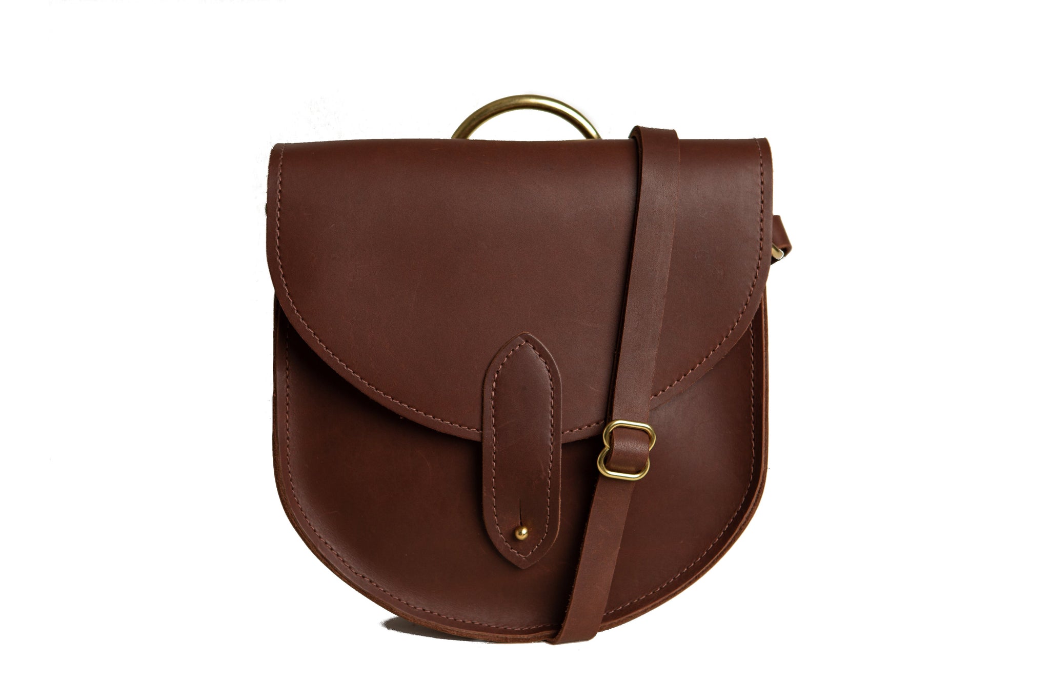 A stylish brown leather saddle bag with gold hardware sits against a white backdrop.
