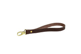 A brown leather wristlet keychain with gold hardware displays the "Urban Southern" logo.
