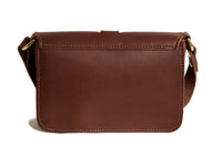 The brown leather crossbody bag features detailed stitching and a gold buckle closure.

