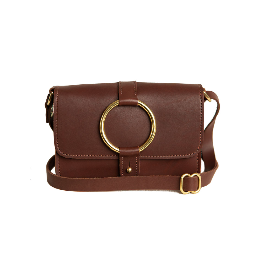 A stylish brown leather crossbody bag features a gold circular handle and strap buckle.
