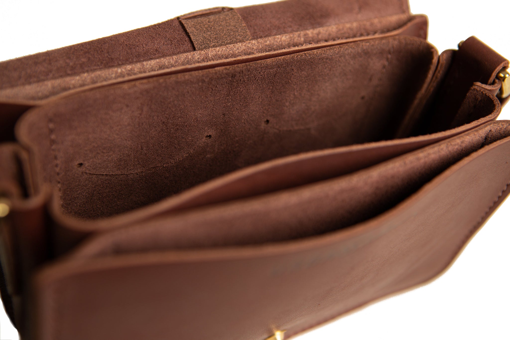 Open brown leather satchel reveals soft suede interior and multiple compartments.

