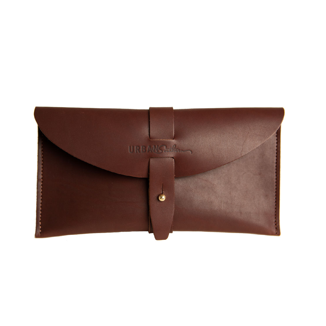 Close-up presents a stylish brown leather clutch featuring a tab closure and the "URBAN Southern" logo.
