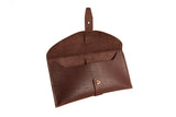 Open brown leather clutch wallet displays its interior and brass button closure.
