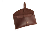 Open brown leather clutch wallet displays its interior and brass button closure.
