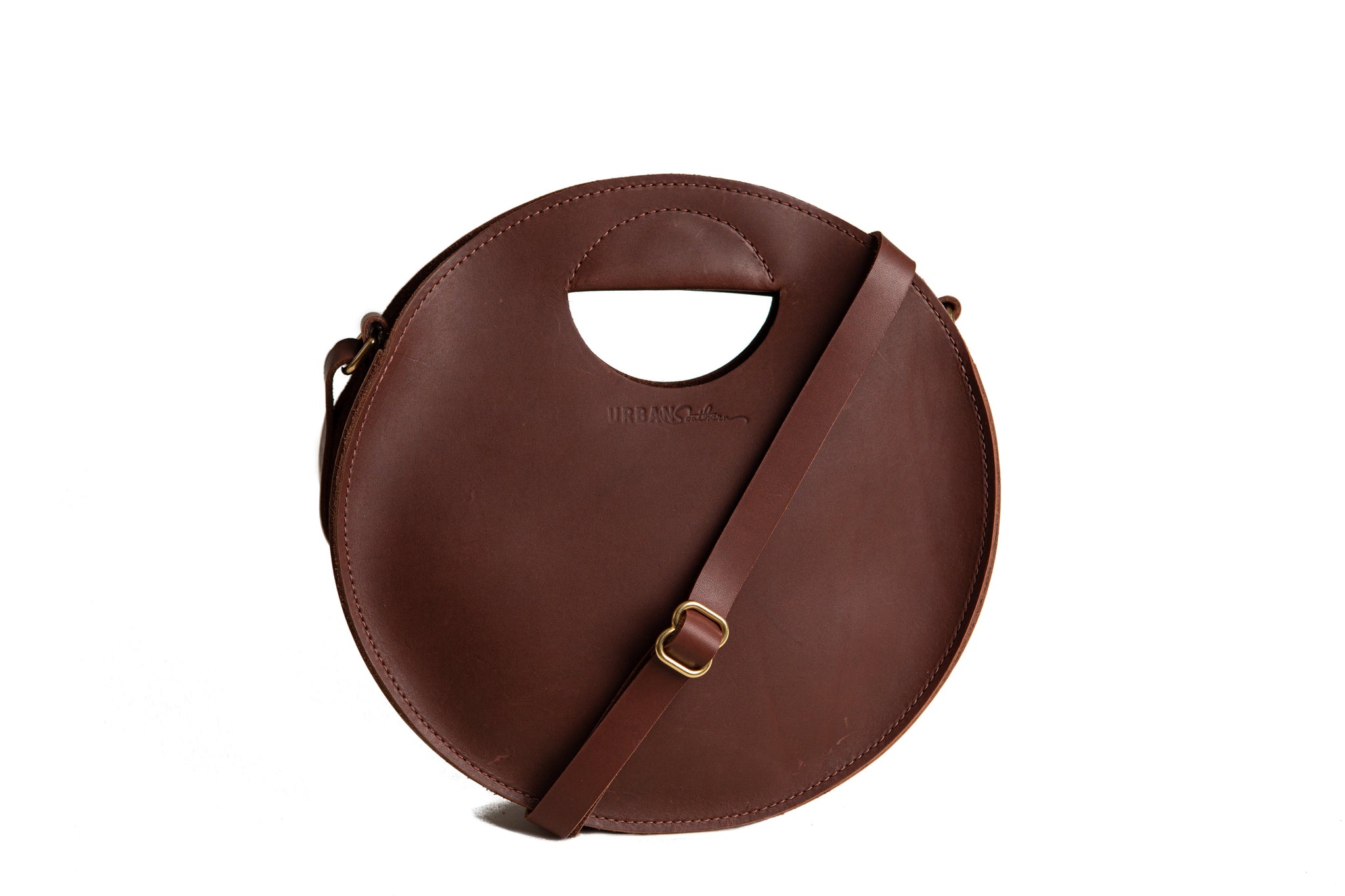 Showcases a stylish round leather handbag with a handle and shoulder strap against a white background.

