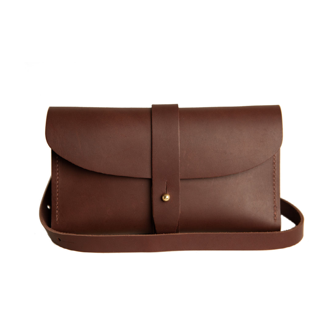 A brown leather crossbody bag closes with a strap and brass button.

