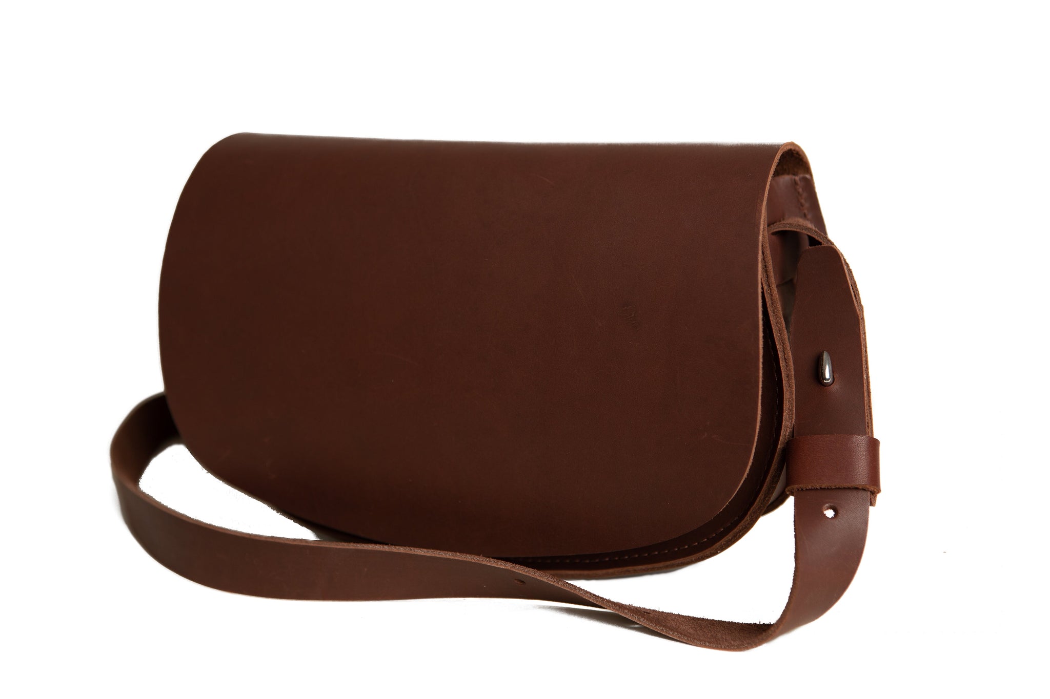 A brown leather satchel handbag with an adjustable shoulder strap sits on a white background.

