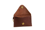 An open, handcrafted brown leather coin purse wallet with a brass snap showcases its minimalist design.
