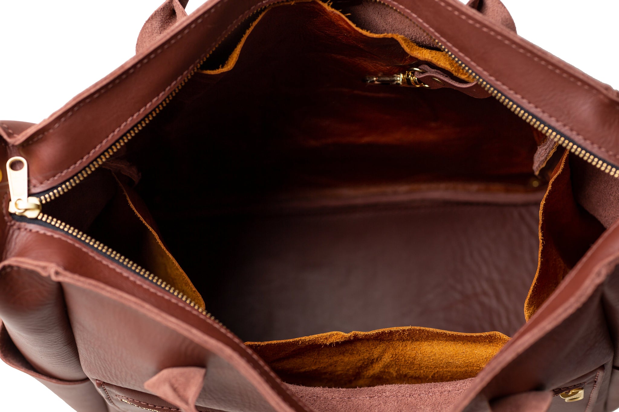 A brown leather tote bag reveals its spacious interior with a golden zipper.
