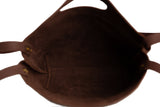 View inside a brown leather tote bag reveals its soft suede lining and durable construction.

