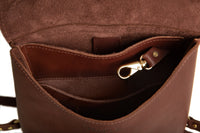 A close-up shows the interior of a brown leather crossbody bag with a gold-colored clasp and multiple compartments.
