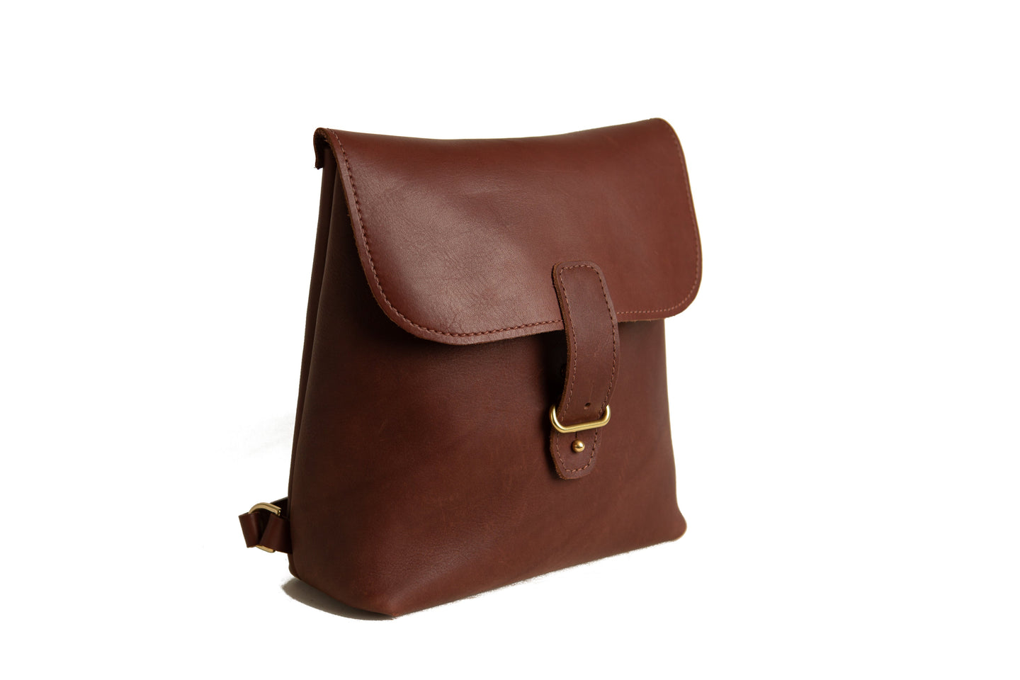 A brown leather backpack with a flap closure sits against a white background.
