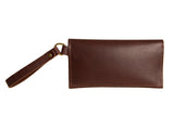 A brown leather wristlet clutch bag displays its craftsmanship with detailed stitching and a brass-tone loop.

