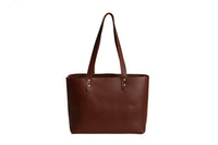 Displaying a stylish, handcrafted brown leather tote bag with long handles.
