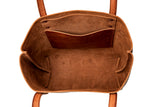 The inside of a brown leather tote bag reveals pockets and compartments.
