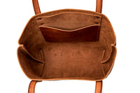 The inside of a brown leather tote bag reveals pockets and compartments.
