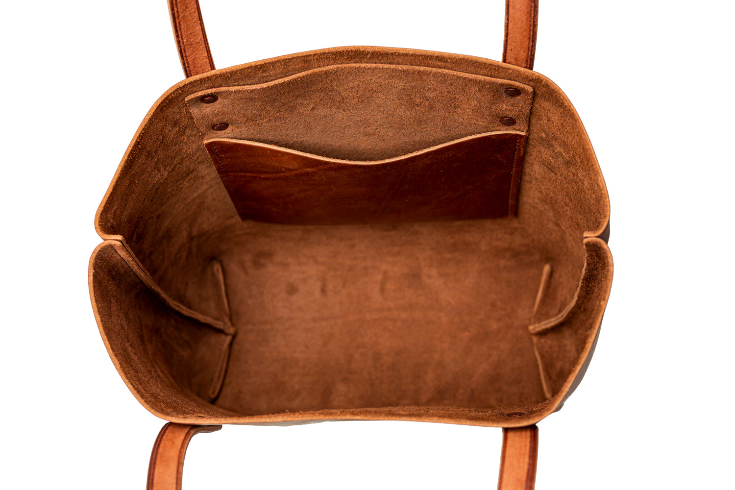 The inside of a brown leather tote bag reveals pockets and compartments.
