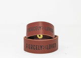 Two brown leather bracelets display the phrase "FIERCELY LOVED" in black lettering.

