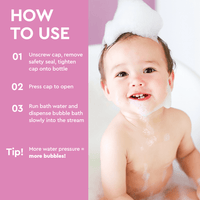 A happy baby enjoys a bubble bath with a foam crown on its head, next to bubble bath instructions.
