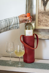 A woman prepares to pour a chilled bottle of Stella Rosa white wine into two wine glasses, presented in a stylish red leather wine tote.
