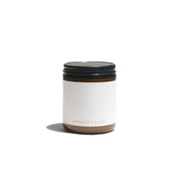 A scented candle labeled "smoked santal" sits isolated on a white surface, casting a soft shadow.
